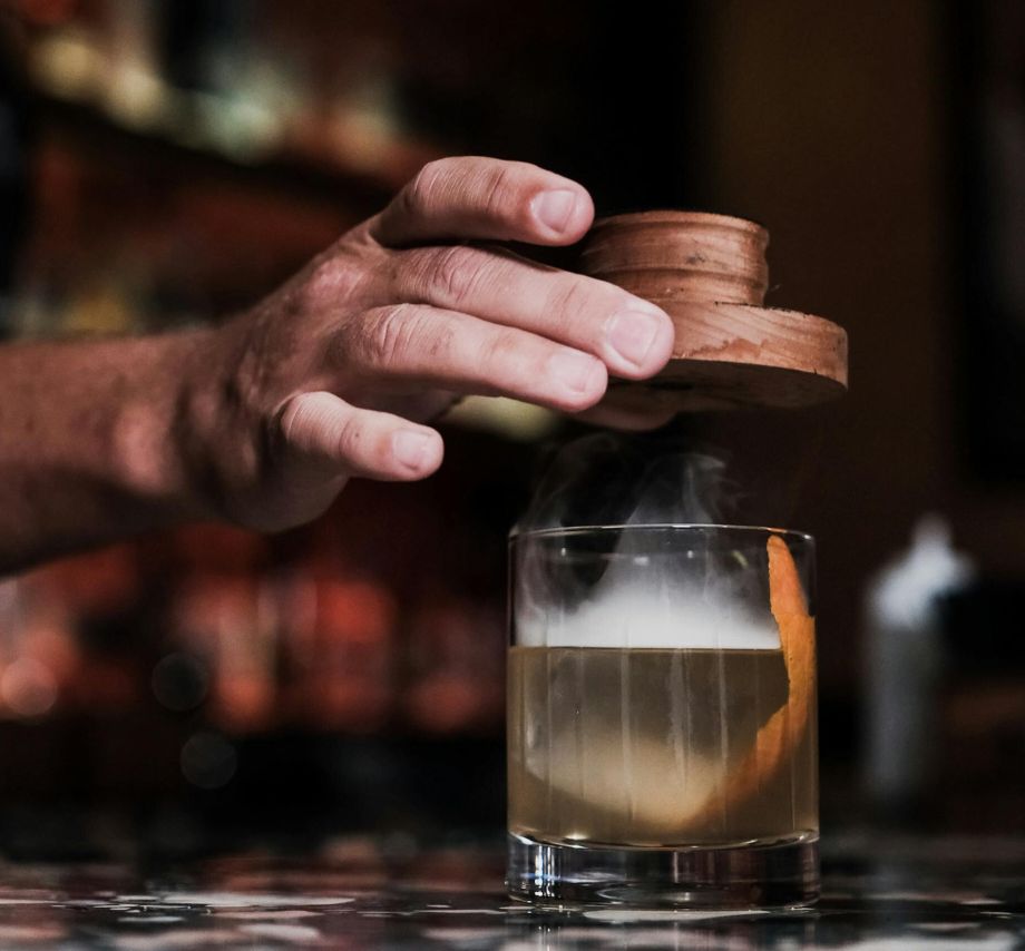 A Professional bartender creating a smoked cocktail.