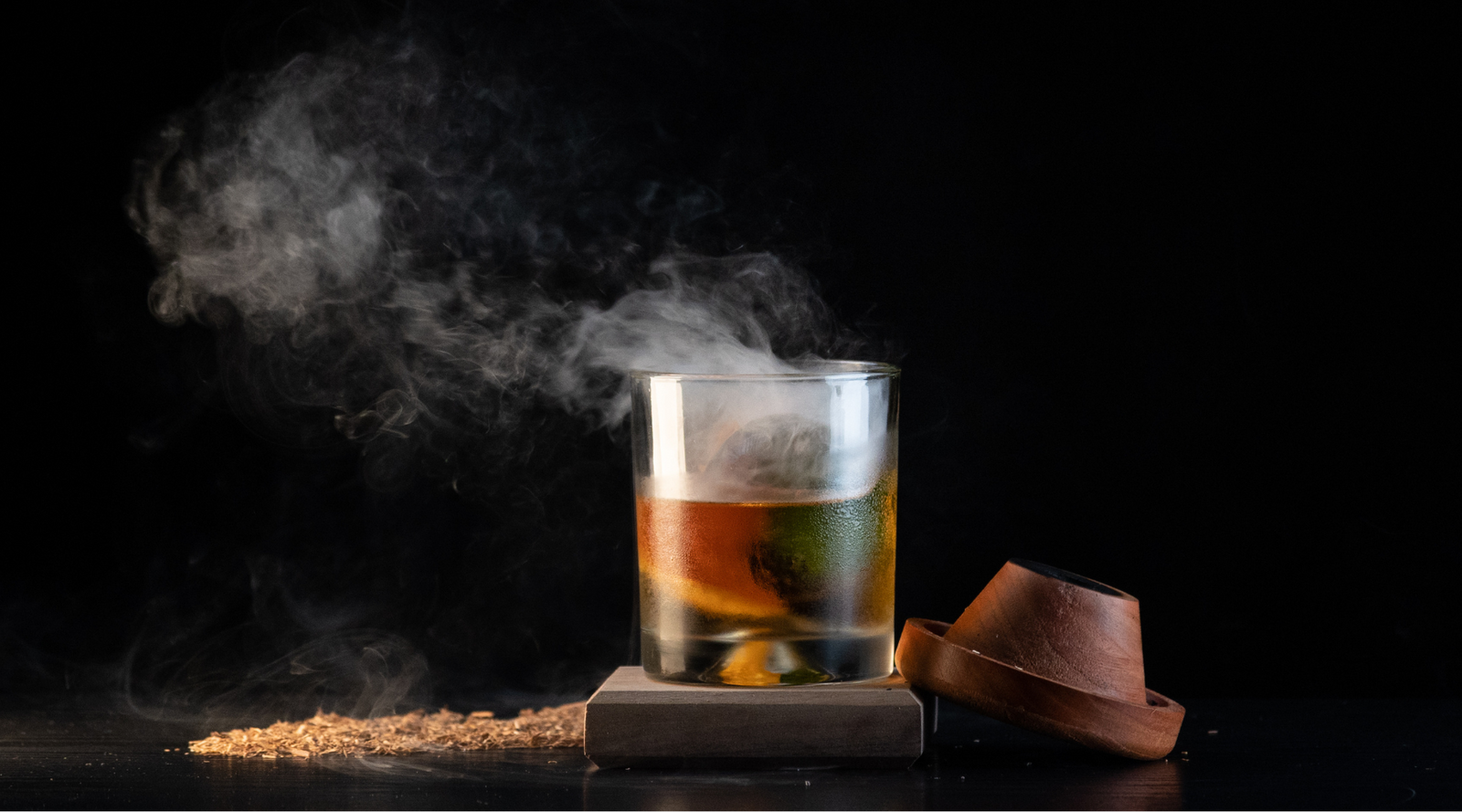 Smoked Old Fashioned cocktail garnished with an orange peel and smoky swirl.